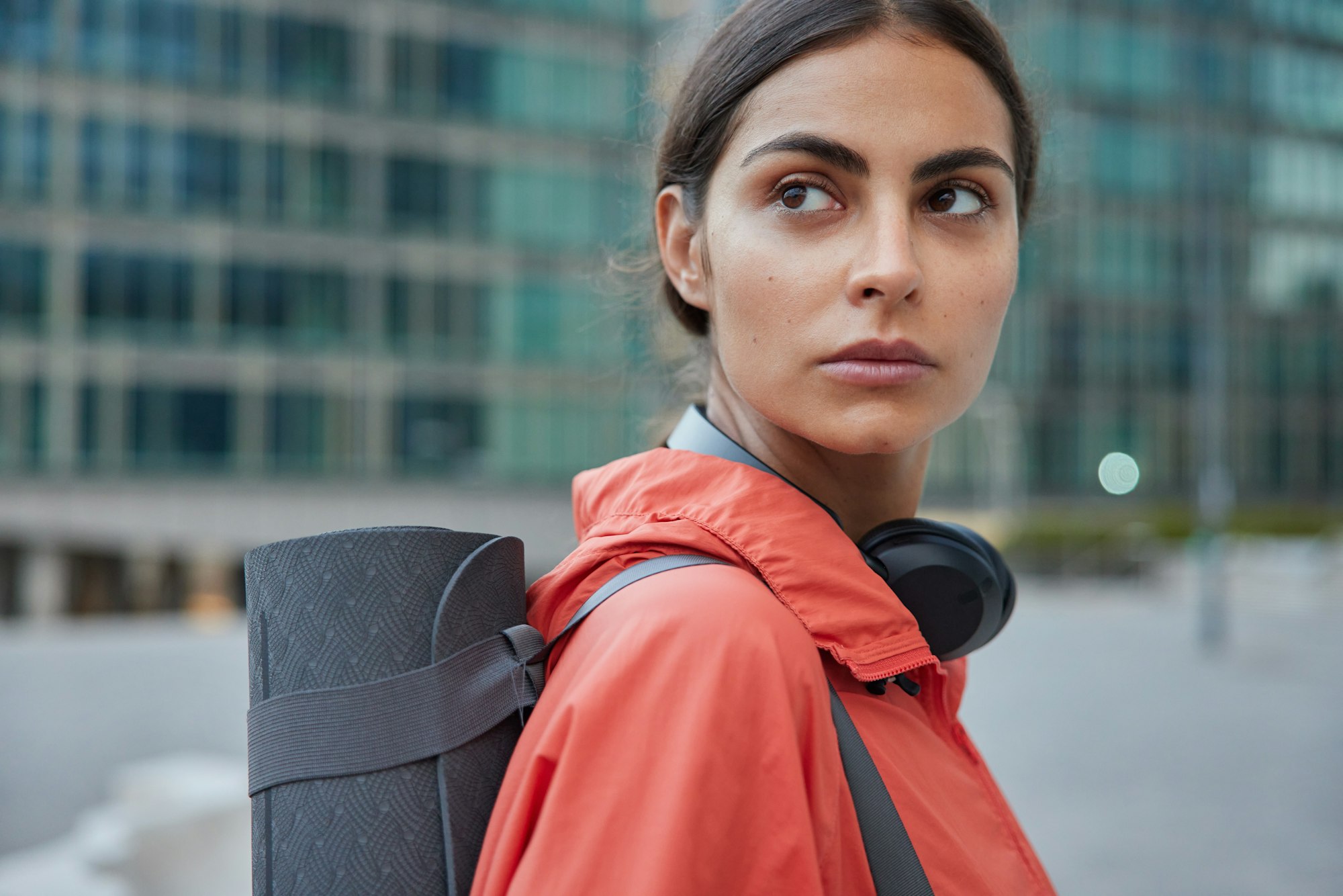 Female yoga trainer waits for someone at street has workout break restrores strength after training