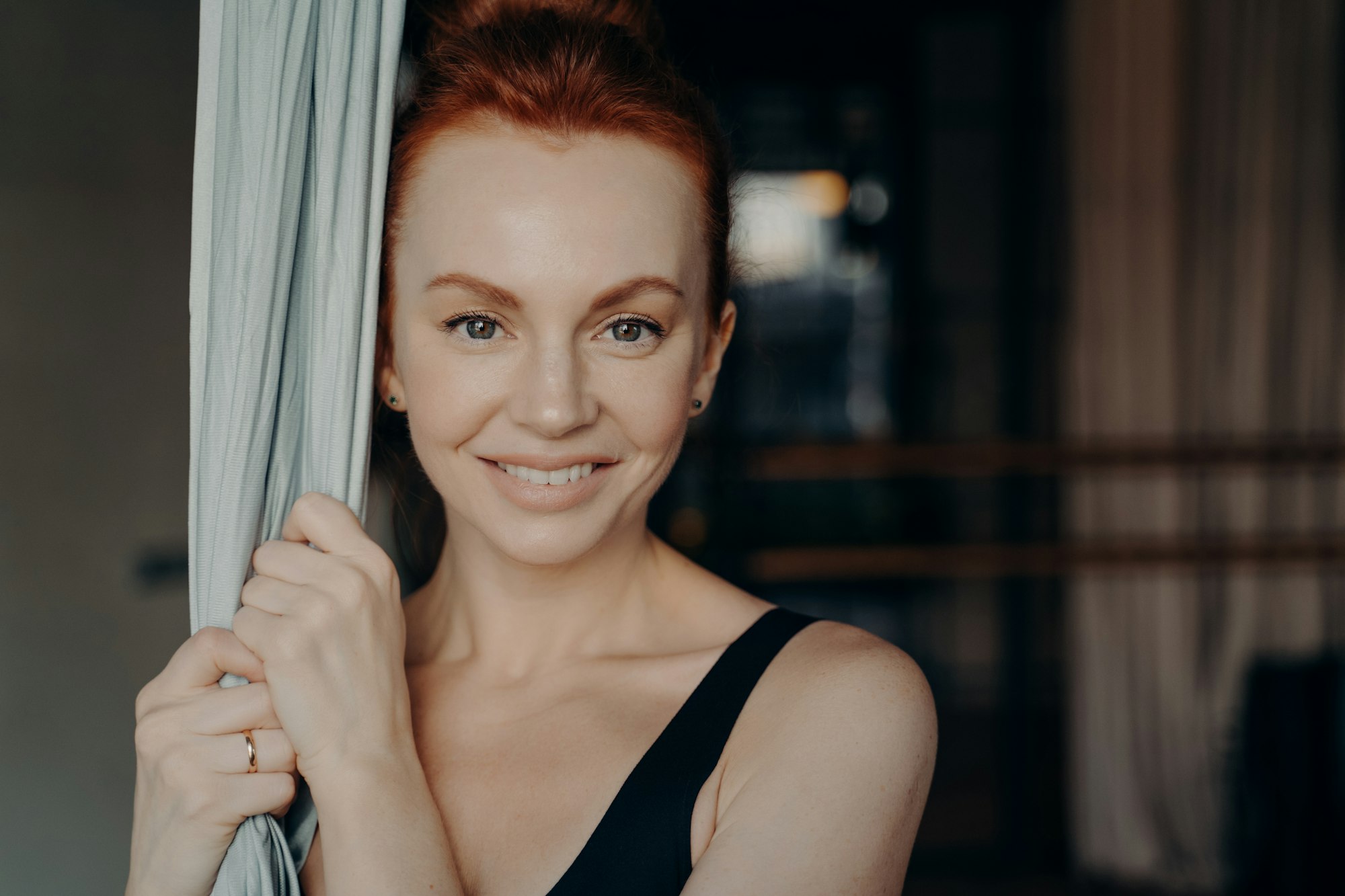 Young beautiful lady with red hair holding yoga hammock